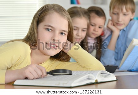boy and three girls doing homework together at the table at home boy and three girls doing homework together at the table at home