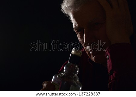 lonely old man drinking alcohol on a black background
