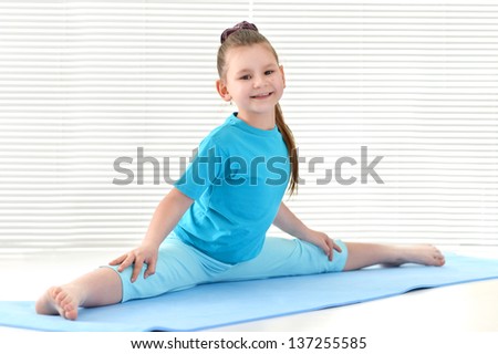 little girl in a blue t-shirt training in the gym