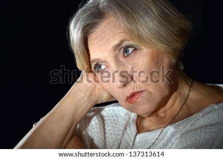 portrait of thoughtful older woman in white on a black background