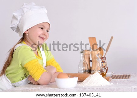 little girl in chef hat and apron  preparing  in the kitchen