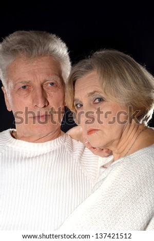 close-up portrait of an elderly couple embracing on a black background