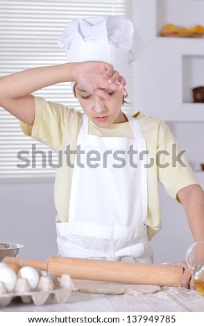 young boy in a chef\'s hat knead dough for cookies