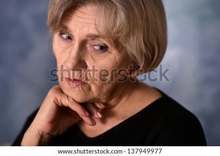 close-up portrait of an thinking elderly woman  on a gray background