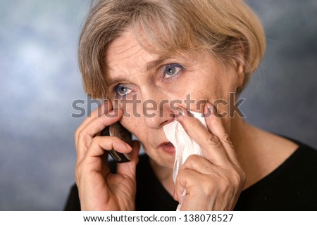 portrait of an old woman crying on a gray background