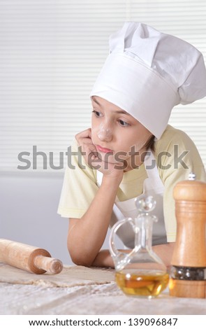 young boy in a chef\'s hat knead dough for cookies