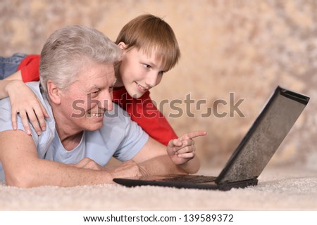 An elderly man and his grandson resting a laptop
