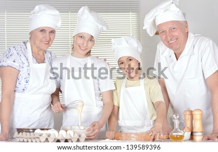 elderly couple and their grandchildren kneading the dough for the cake together