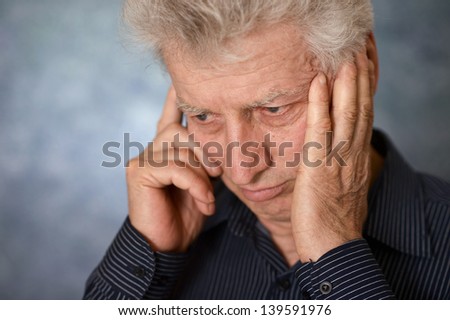 portrait of a sad old man calling on a gray background