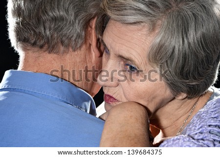 Portrait of older couple embracing on a black background