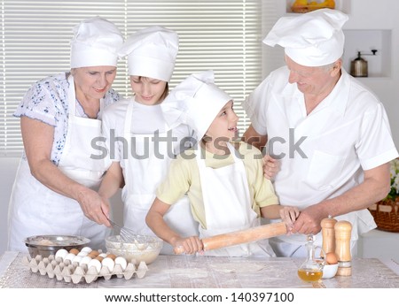 elderly couple and their grandchildren kneading the dough for the cake together