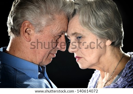Portrait of an elderly couple embracing on a black background