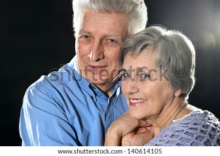 Portrait of older couple embracing on a black background