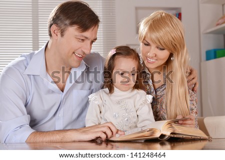 happy parents reading a book their daughter at home