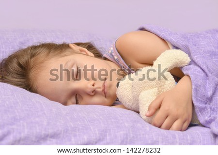 cute little girl sleeping with a toy in her bed