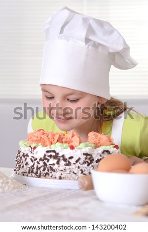 little girl in chef hat with a sweet cake