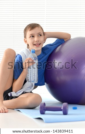 sporty young boy in a blue shirt with gymnastic ball
