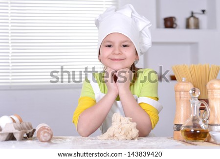 lovely girl in a hat chef knead the dough for the cake