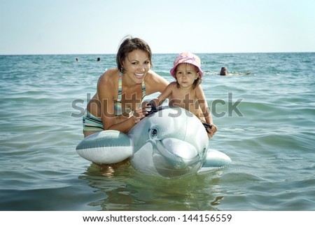 Mom with her daughter and an inflatable dolphin swim in the sea