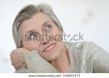 Portrait of an aged woman in a gray sweater at home