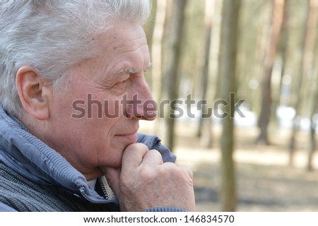 Pensive aged man walking in the forest in autumn