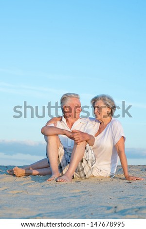 Elderly happy couple relaxing in the sand together