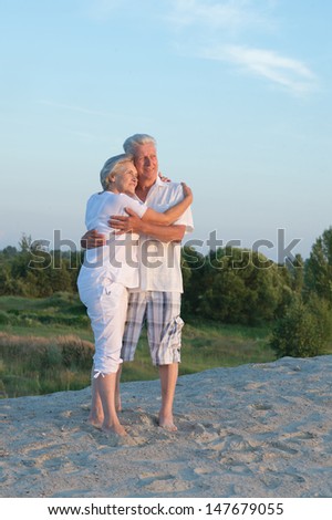 Elderly happy couple relaxing in the sand together
