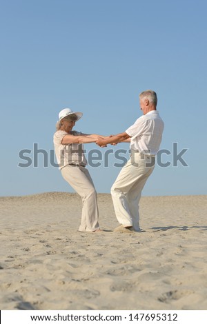 old couple in love walking barefoot in the sand