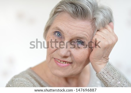 Portrait of an old woman in a gray sweater at home