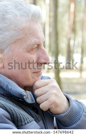 Pensive aged man walking in the forest in autumn