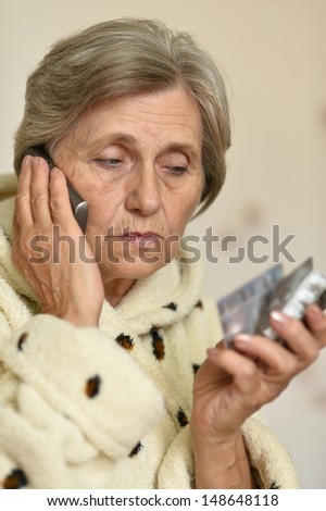 old woman with tablets in hand calling on the phone