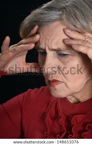sad old woman in red on a black background