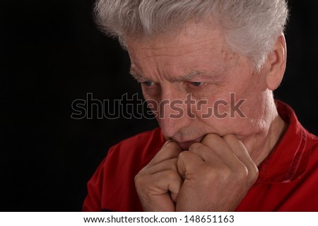 sad old man in red on a black background