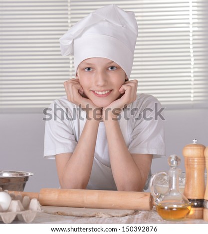 Young boy in a chef\'s hat knead dough for cookies