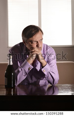 Cute young man drinks whiskey at table