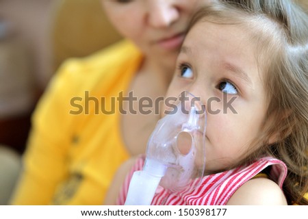little cute girl doing inhalation at home