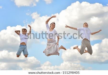 Happy family jumping on a background of blue sky and clouds