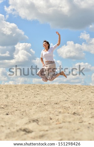 Happy woman jumping on sky and sand background