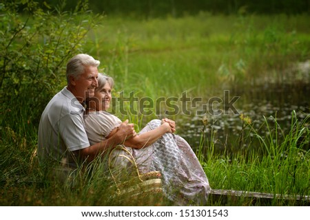 Old man and woman sitting on a grass