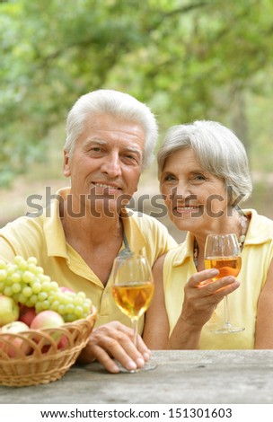 old couple drinking wine and basket of fruits on the table