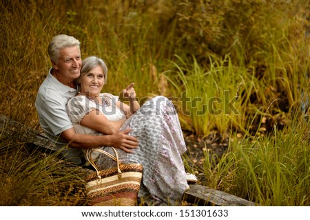 old couple sitting near the lake. Woman pointing something. Vintage photo