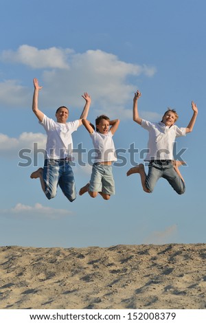 Happy family of three people jumping outdoors