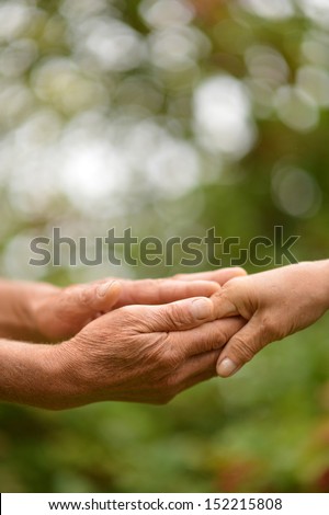 Two hands together against the green natural background