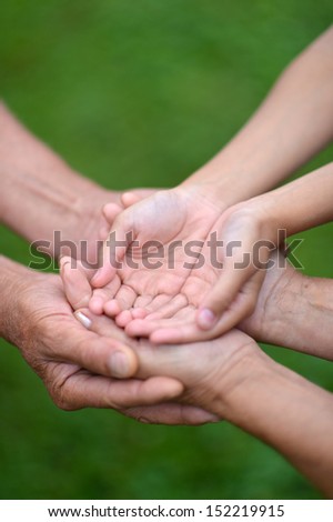 Three pairs of hands are held together. Care concept