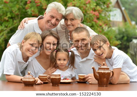 Happy family drinking tea at table outdoors in summer time