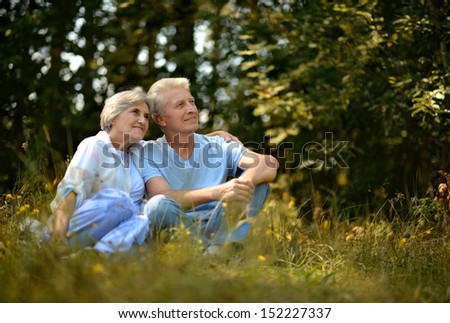 Elderly couple sit on a ground in summer forest