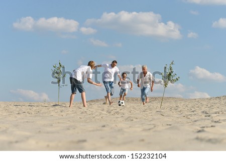 Happy family playing soccer outdoors