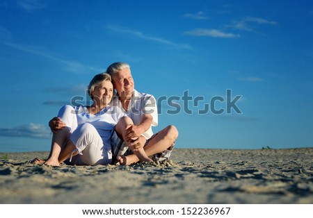 Elderly Happy Couple Relaxing In The Sand Together