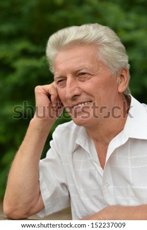 Old smiling man out for a walk in the park in summer