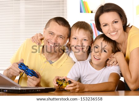 Family of four having fun playing video games on laptop